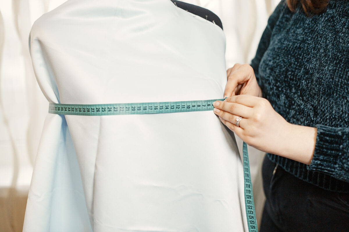 women measuring dummy with white top using centimetre tape