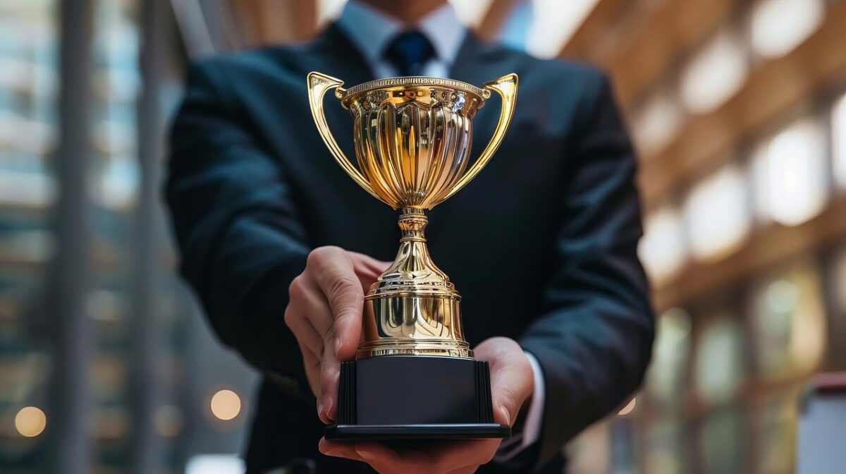man in blue suit holding trophy cup