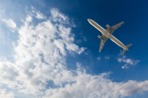 A passenger jet airplane flying through a blue cloudy sky.
